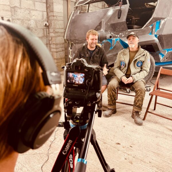 A crew interview being filmed in a workshop, in front of a Mega City One cab under restoration